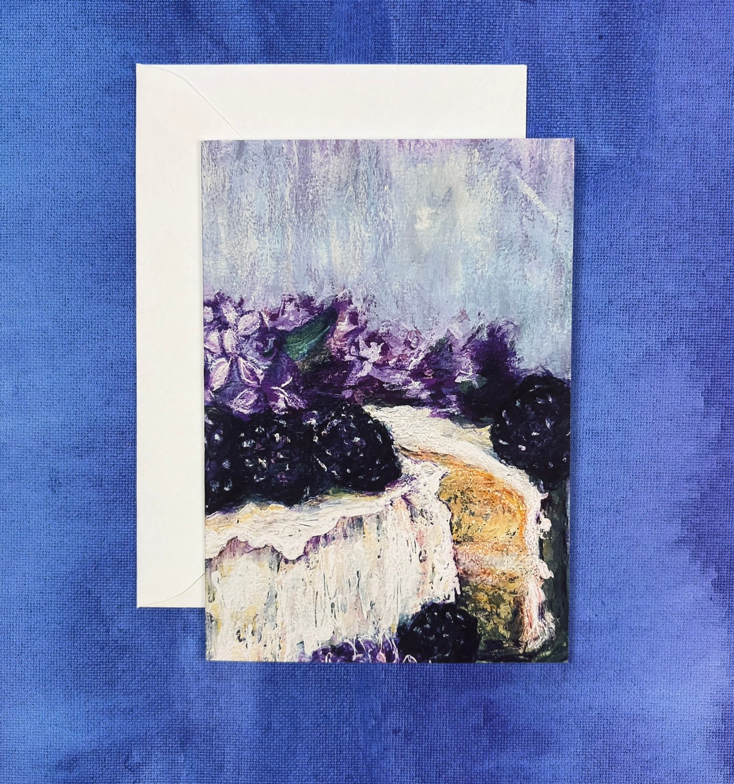 Greeting card with a painting of a cake with purple lilac flowers and blackberries on a blue background