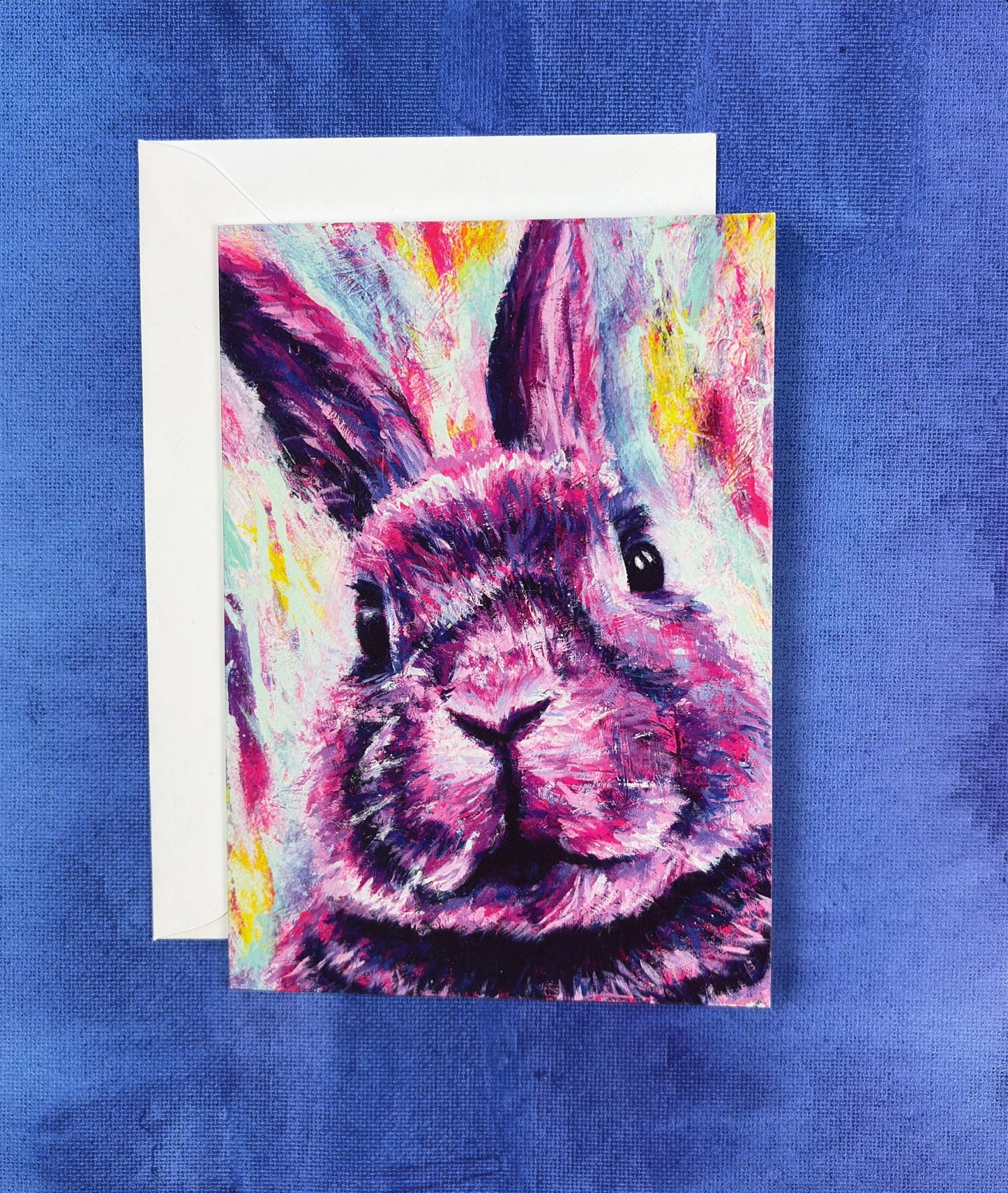 Colorful pink rabbit painting on a greeting card with a purple background