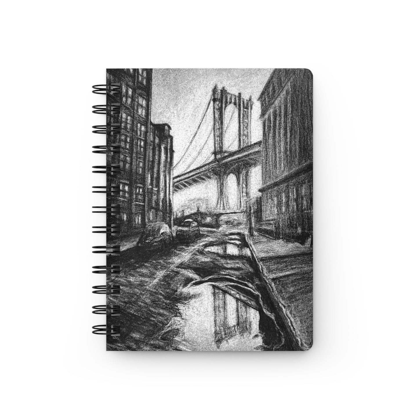 A spiral notebook with a charcoal drawing of an urban scene on the cover, featuring a bridge and buildings.
