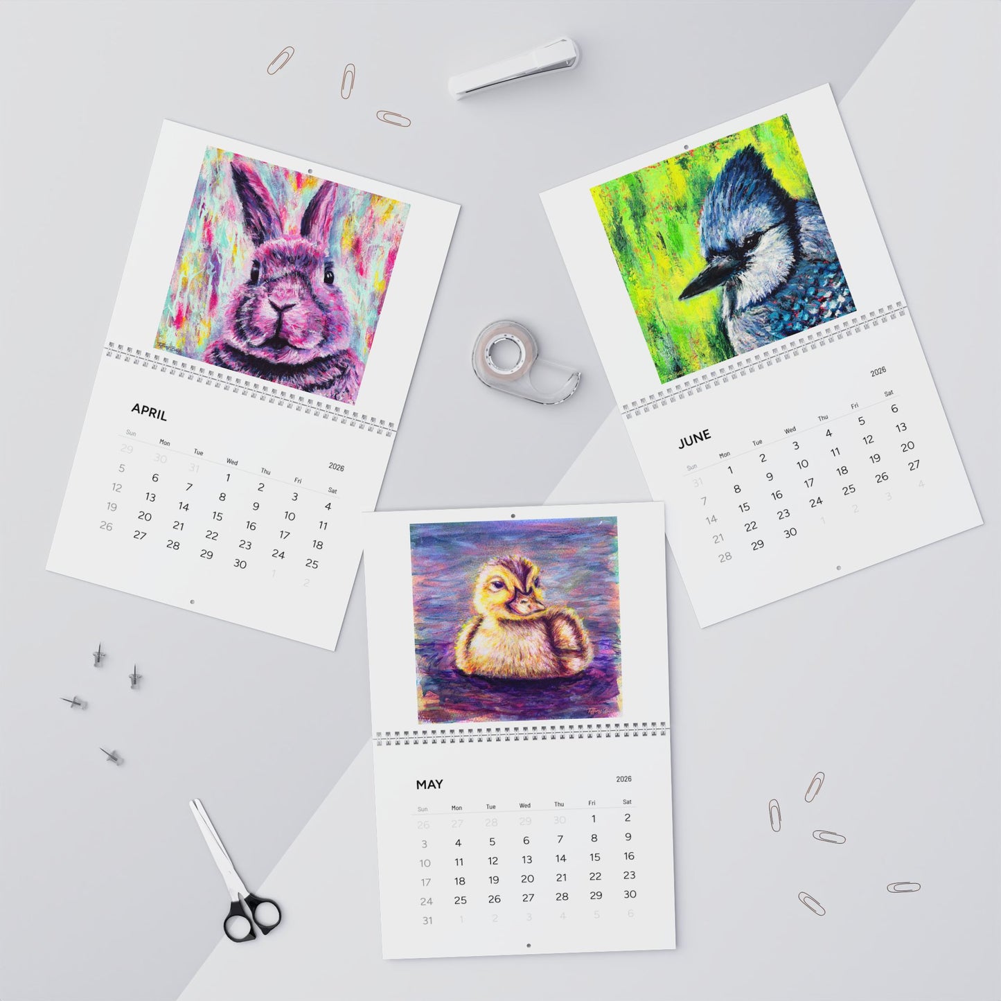 Four calendar pages showing colorful animal illustrations on a gray surface.