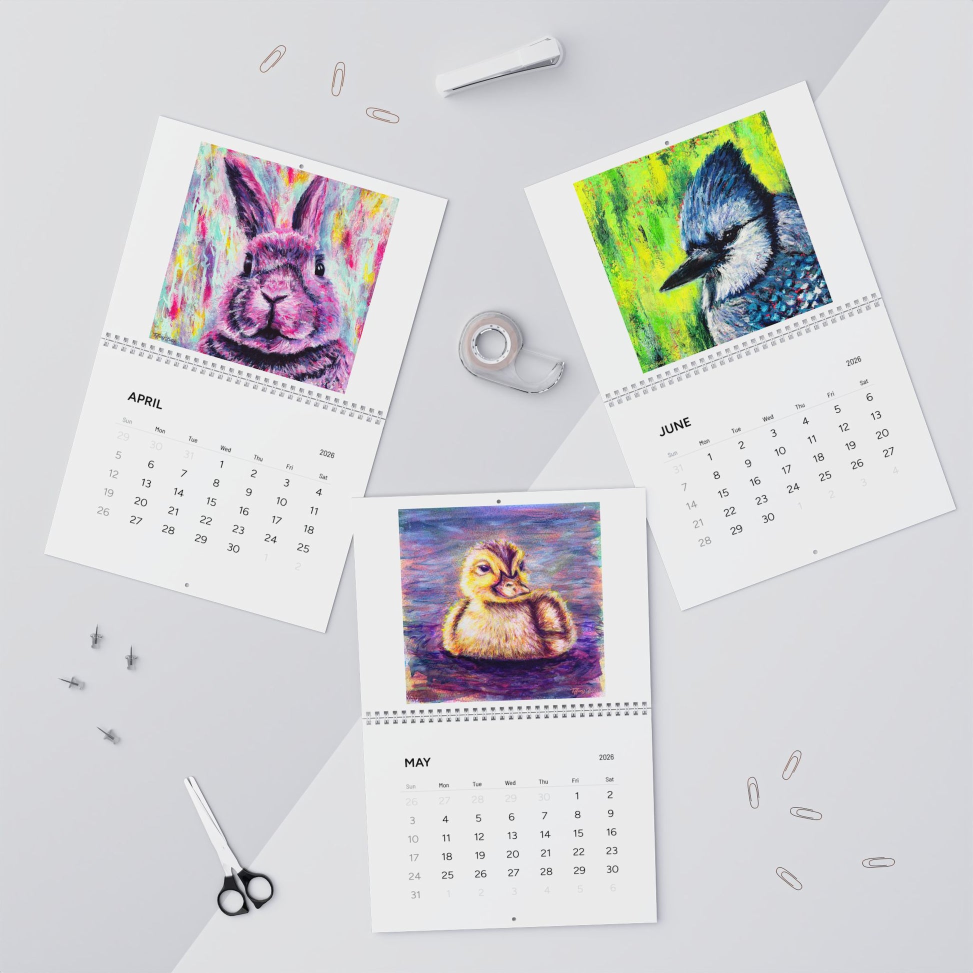 Four calendar pages showing colorful animal illustrations on a gray surface.