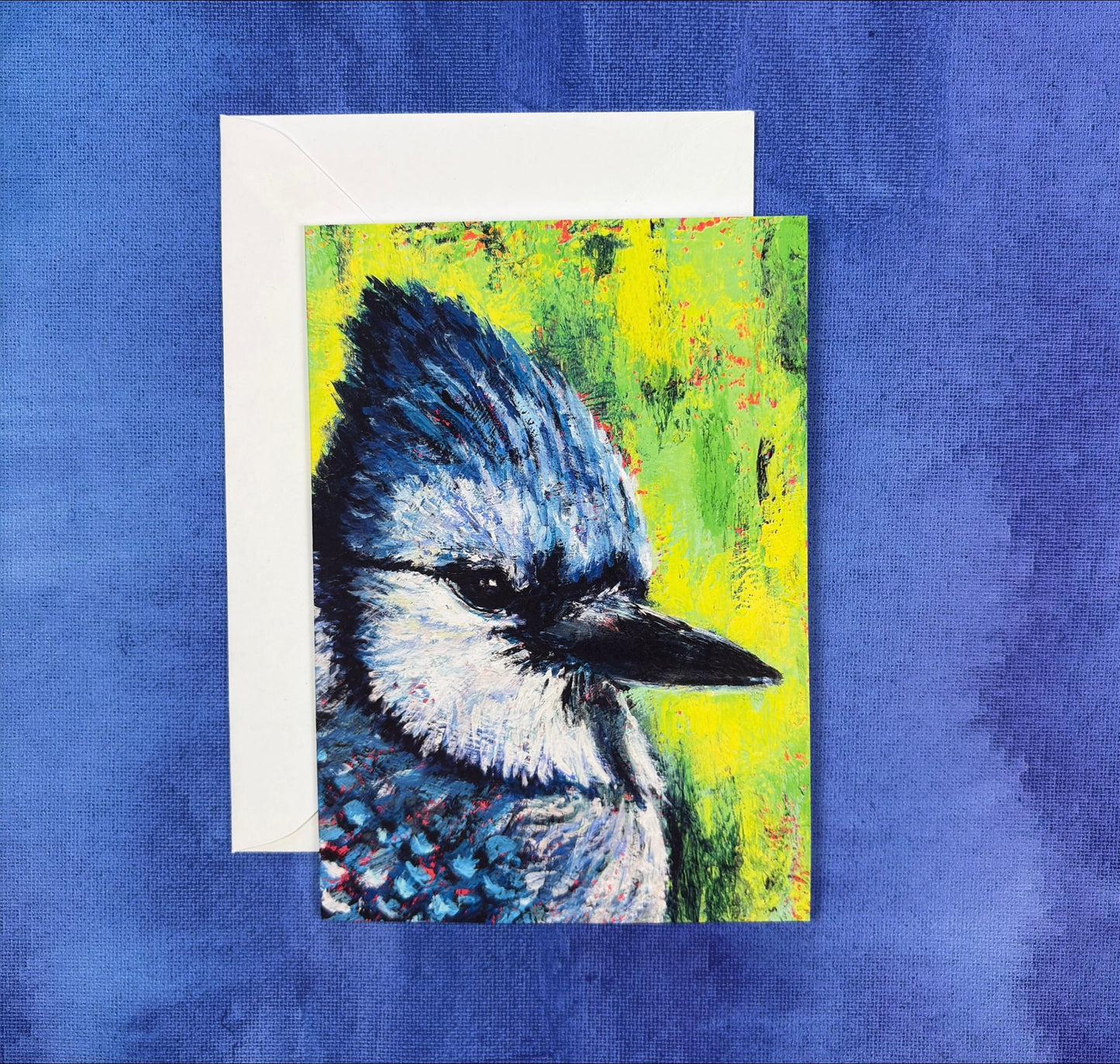 Greeting Card with a vibrant blue jay painting with a green background on a blue background
