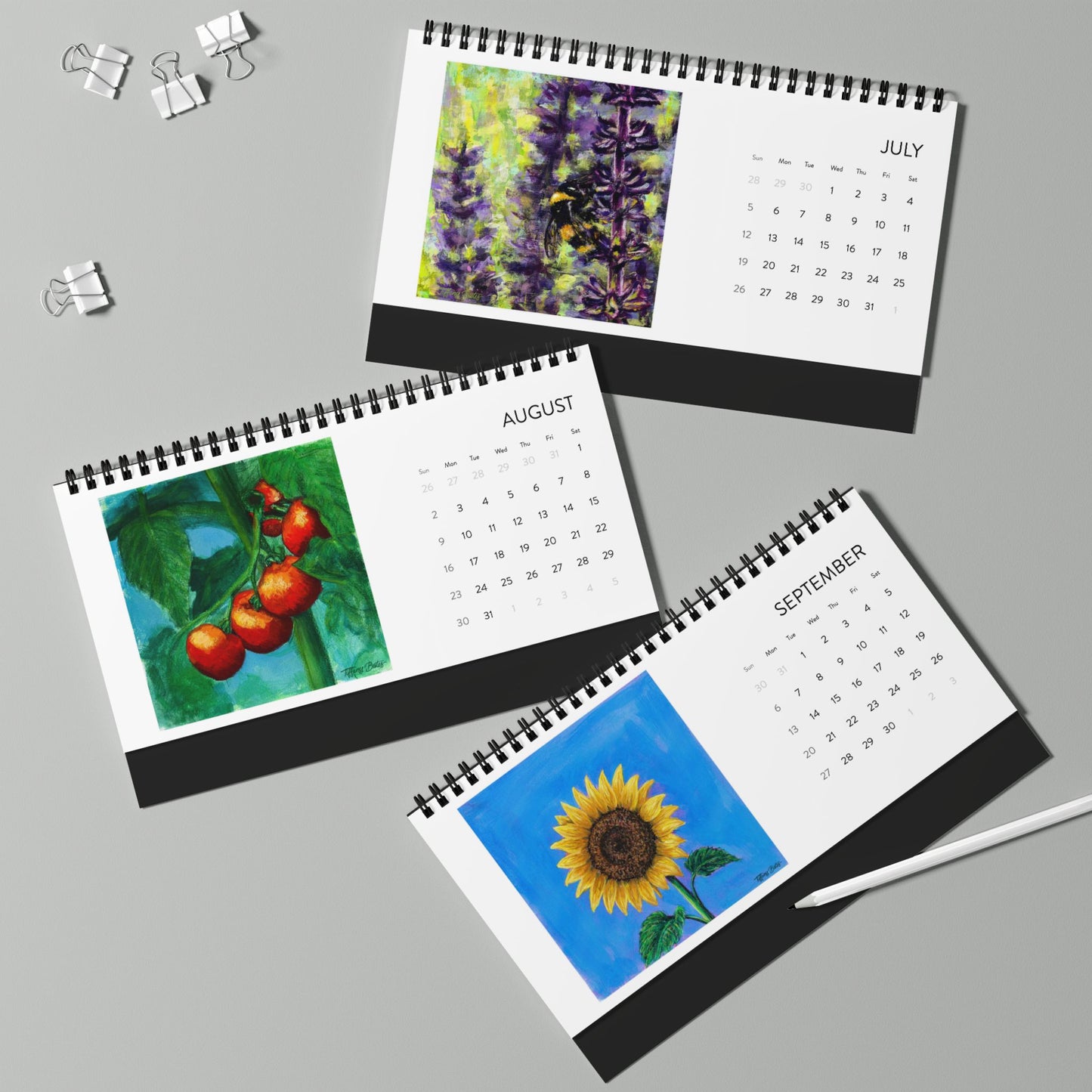 Three spiral-bound calendars for July, August, and September on a gray background.