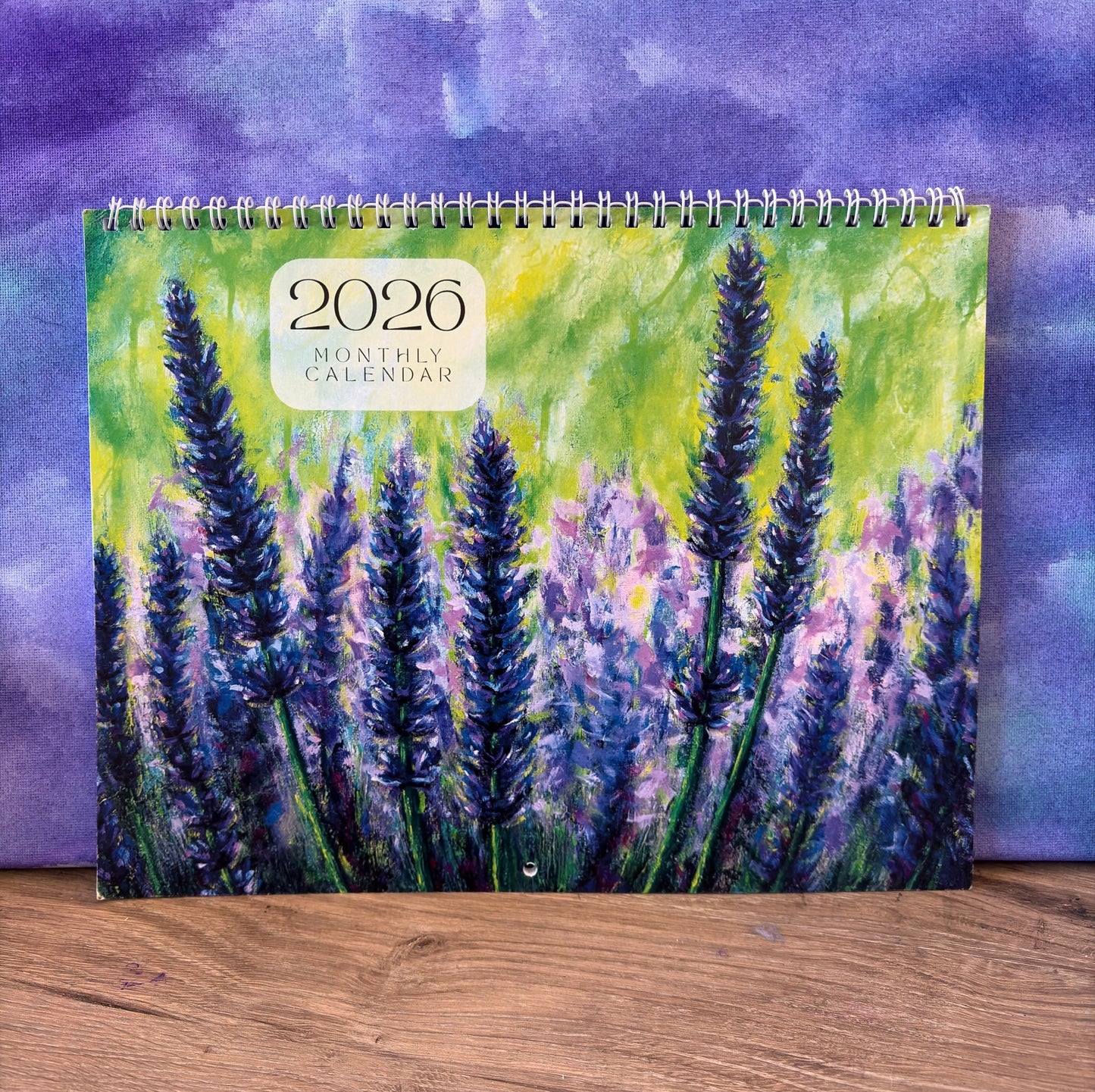 2026 calendar with lavender design on a wooden surface and purple watercolor background