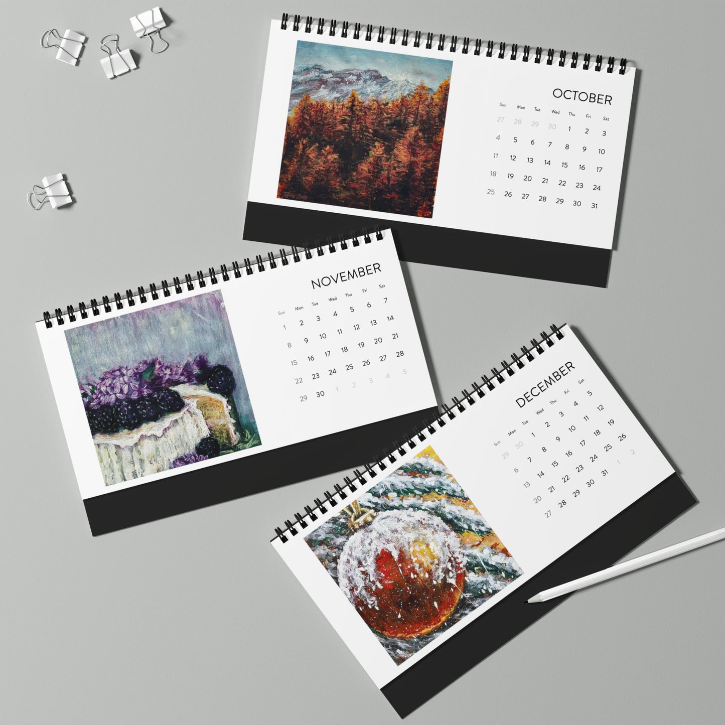 Three spiral-bound calendars for October, November, and December on a gray background.