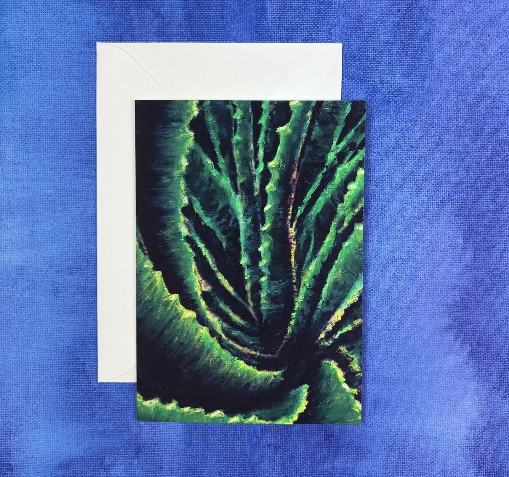 Greeting card with green abstract aloe plant design on a blue textured background