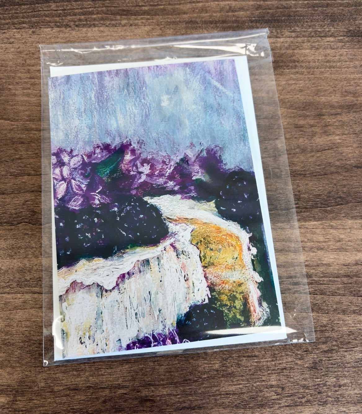 Greeting card with a painting of a cake with purple lilac flowers and blackberries in a clear bag